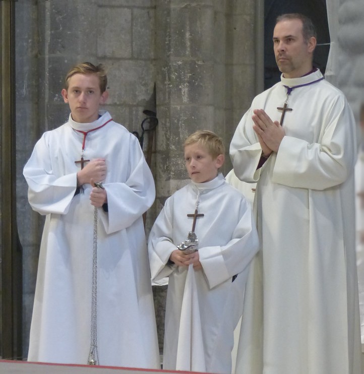 Photo de trois servants d'autel portant les cordons blanc, rouge et violet